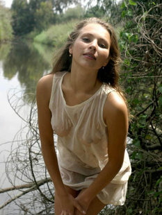 Демонстрирует обнаженное тело на природе